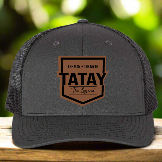 Gray trucker cap with brown and black graphic text 'TATAY' on a white background